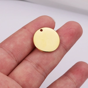 Polished 18k gold stainless steel round charm pendant shown between fingers for scale