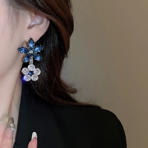 Close-up of elegant blue and clear cubic zirconia flower drop earrings on a model