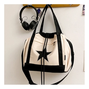 Detail of canvas crossbody bag with large star logo, drawstring and zipper pocket