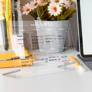 Detailed view of an acrylic weekly to-do list board with metal stands on a tidy desk