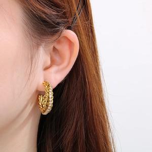 Elegante goldene gedrehte C-Ohrringe mit Diamantbesatz an einem Model gezeigt