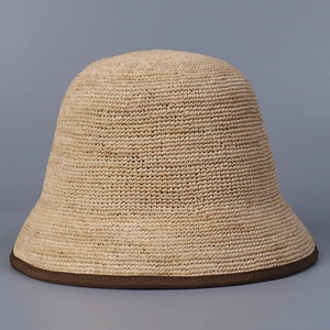 Detailed texture of raffia straw bucket hat with dark brown fabric edge binding trim