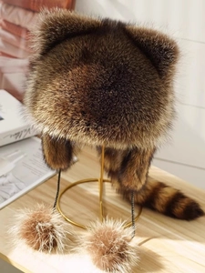 Detail of faux fur animal hat with fluffy ears and large pom-pom decorative tassels