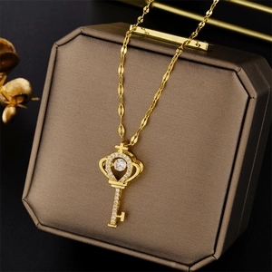 Elegant gold crown key necklace with a dancing central diamond on a luxury jewelry box