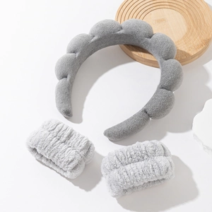 Detail of grey sponge spa headband and matching plush wristbands on white background