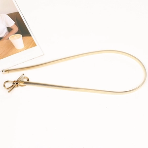 Detail of a golden metal elastic waist belt with a stylish bow buckle on white background