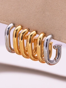 Vue macro de boucles d'oreilles en U en or 18 carats et argent sur support beige
