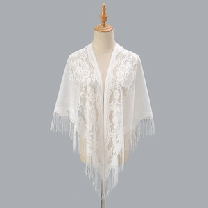 Dettaglio scialle in pizzo bianco con ricami floreali e lunghe frange con nappine