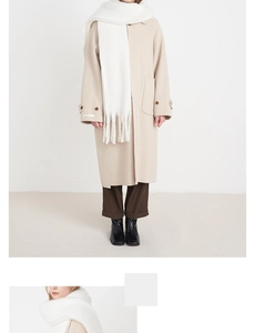 Detail of soft beige faux cashmere scarf with thick tassels paired with a wool coat