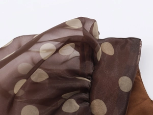 Detail of brown organza fabric with large beige polka dots and a lightweight texture