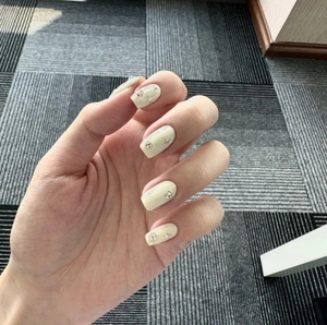 Minimalist beige press-on nails with silver star patterns and 3D rhinestone accents