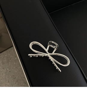 Macro shot of silver bow metal hair claw clip with elegant hollow design on black leather