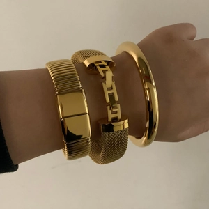 Three-piece gold stainless steel bracelet set featuring chain links and open cuff on wrist
