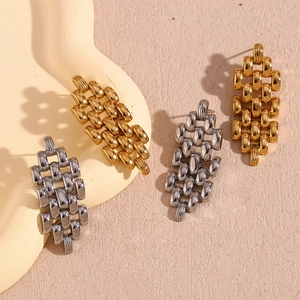 Detailed close-up of golden and silver watch-band link earrings on a model ear