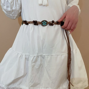 Detail of bohemian braided waist chain featuring turquoise flower buckle and tassels