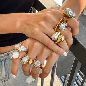 Detail of hand wearing layered gold baroque pearl rings in stainless steel