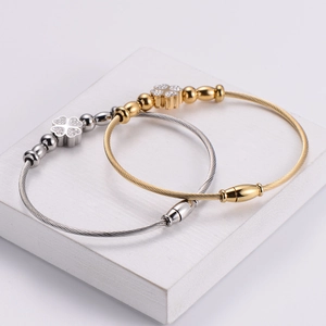 Detail showing the braided wire texture and stone-set clover charm on the bangle