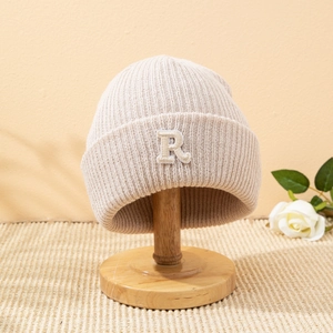 Berretto in maglia a coste beige con lettera R ricamata su supporto in legno e rosa decorativa