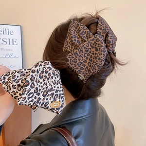 Detail of leopard print bow hair claw clips with gold logo on stylish ponytail