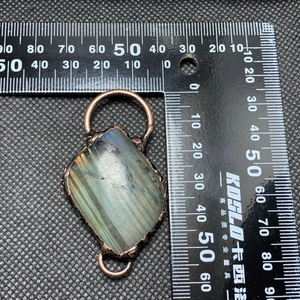 Macro view of vintage labradorite stone pendant with bronze wire wrap and scale measurement