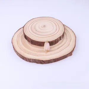 Detail of copper wire-wrapped pink natural stone rectangular pendant on wood base
