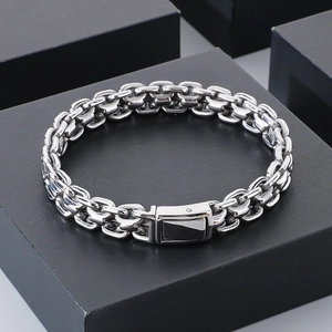Detailed close-up of polished silver curb chain links and sturdy clasp on black display