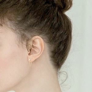 Close-up of elegant gold chain drop earrings with sparkling studs worn by a model