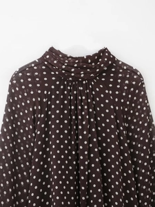 Dettaglio del collo alto con ruches sulla camicia in chiffon marrone scuro a pois bianchi