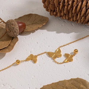 Detailed view of a gold butterfly bracelet with metallic beads on a natural background
