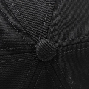 Détail du bouton supérieur et des coutures sur la casquette en coton brodée aigle