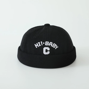 Détail du bonnet en tricot noir sans bord avec broderie blanche HI! BABY C de près
