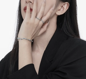 Detailed view of silver rings and bracelets featuring irregular lava textures on a model