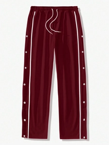 Detail of burgundy joggers featuring white side stripes and snap button side split vents