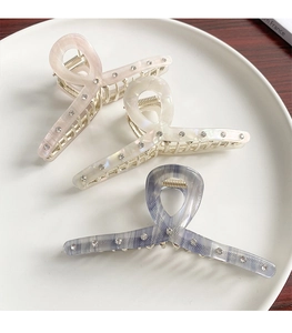 Three acetate hair claws in pink, white and blue-grey with sparkling rhinestones set