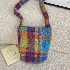Detail of vibrant plaid plush bucket bag with soft wool-like texture in cozy home setting