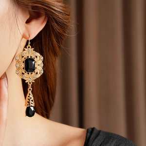 Close-up of vintage baroque style earrings with black gemstones and gold hollow metalwork