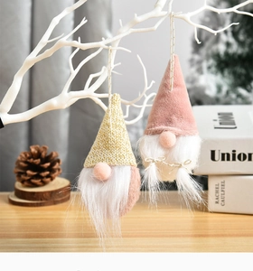 Close-up of cute Christmas gnomes with knit hats hanging on a white decorative branch
