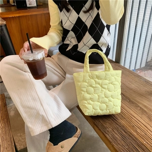 Detail of yellow quilted tote bag featuring a 3D floral pattern and padded nylon texture