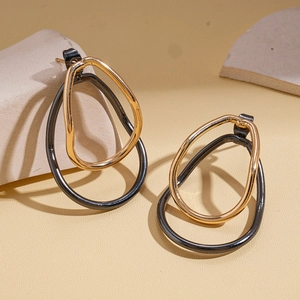 Detail view of oval intertwined gold and black earrings on geometric stone props