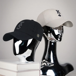 Classic black and off-white baseball caps with embroidered K spade logo on a sleek stand
