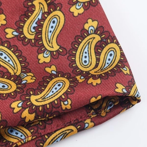 Detailed macro view of red twill fabric with intricate blue and yellow paisley pattern