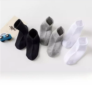 Close-up of three pairs of mesh cotton kids' socks in white, black and grey tones