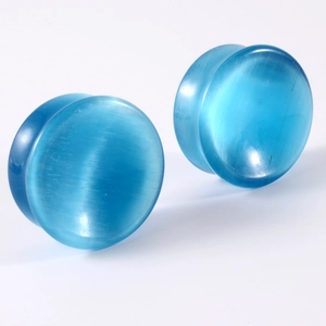 Macro detail of blue natural stone ear plugs with smooth surface and cat-eye finish