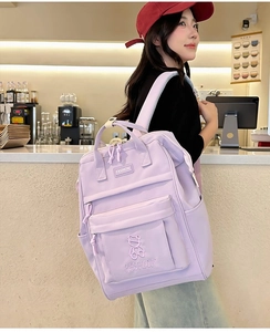 Detail of purple nylon backpack with cute bear embroidery shown on a female model