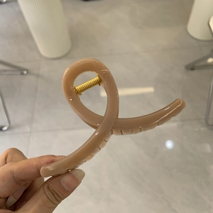 Nahaufnahme der minimalistischen Haarklammer in Altrosa mit robuster goldener Metallfeder