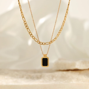 Elegant gold double-layered necklace featuring a rectangular black pendant and Figaro chain