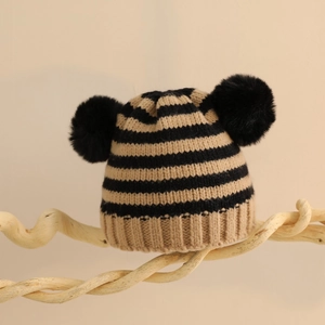 Dettaglio della maglia e doppi pompon su un berretto invernale a righe per neonati