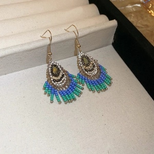Close-up of Bohemian beaded tassel earrings with blue and green beads in a jewelry box