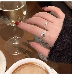 Detailed view of silver heart-shaped ring and twisted band on a hand at teatime