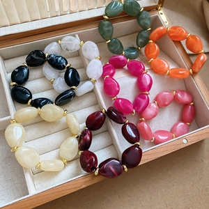 Macro detail of irregular marble-textured acrylic beads with gold spacers in a jewelry box